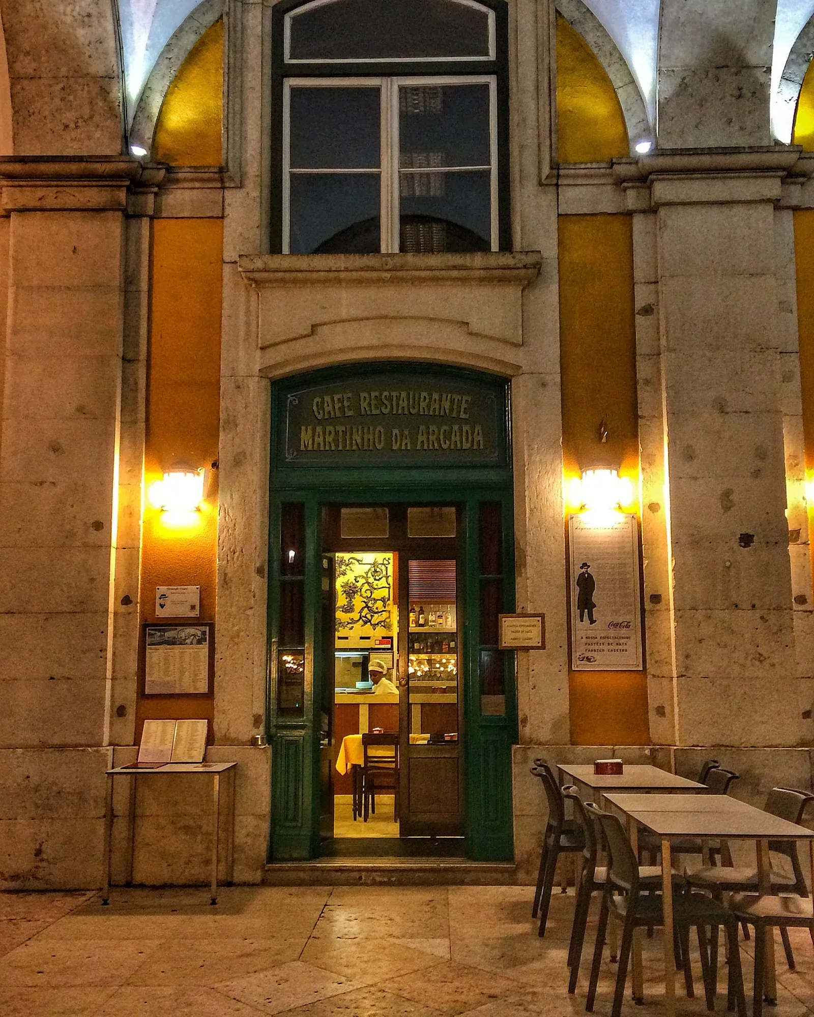 Фасад кафе Martinho da Arcada под аркадами площади Коммерсиу ночью.