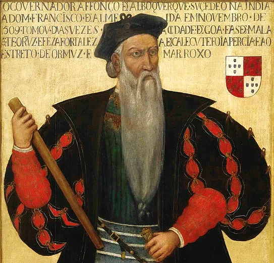 Afonso de Albuquerque de barrete preto e longa barba branca, com um bastão de comando na mão.