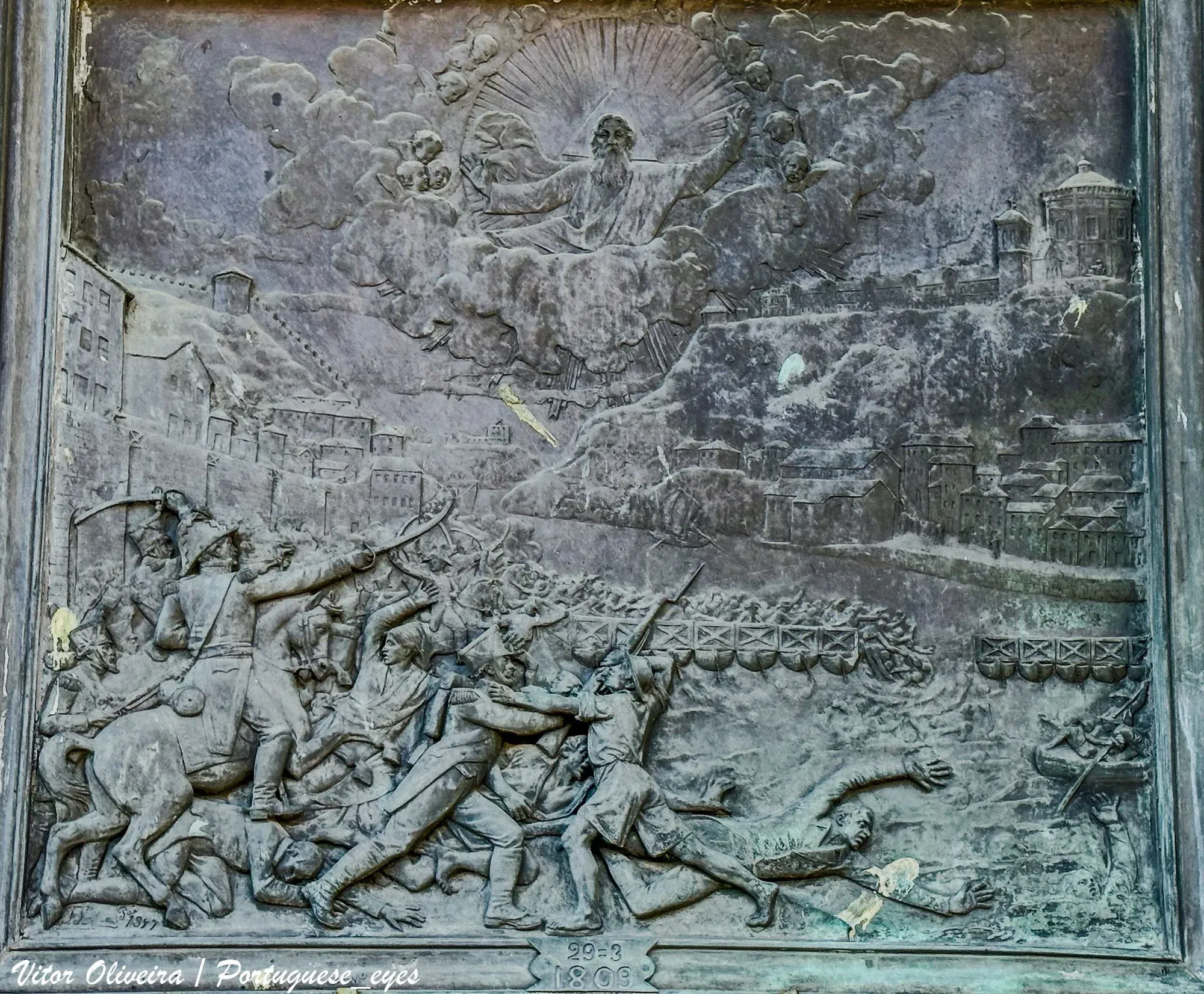 Relevo de bronze das Alminhas da Ponte, na Ribeira do Porto: soldados perseguem a multidão em fuga, que cai ao rio junto à ponte das barcas, e no céu a figura de Deus entre anjos.
